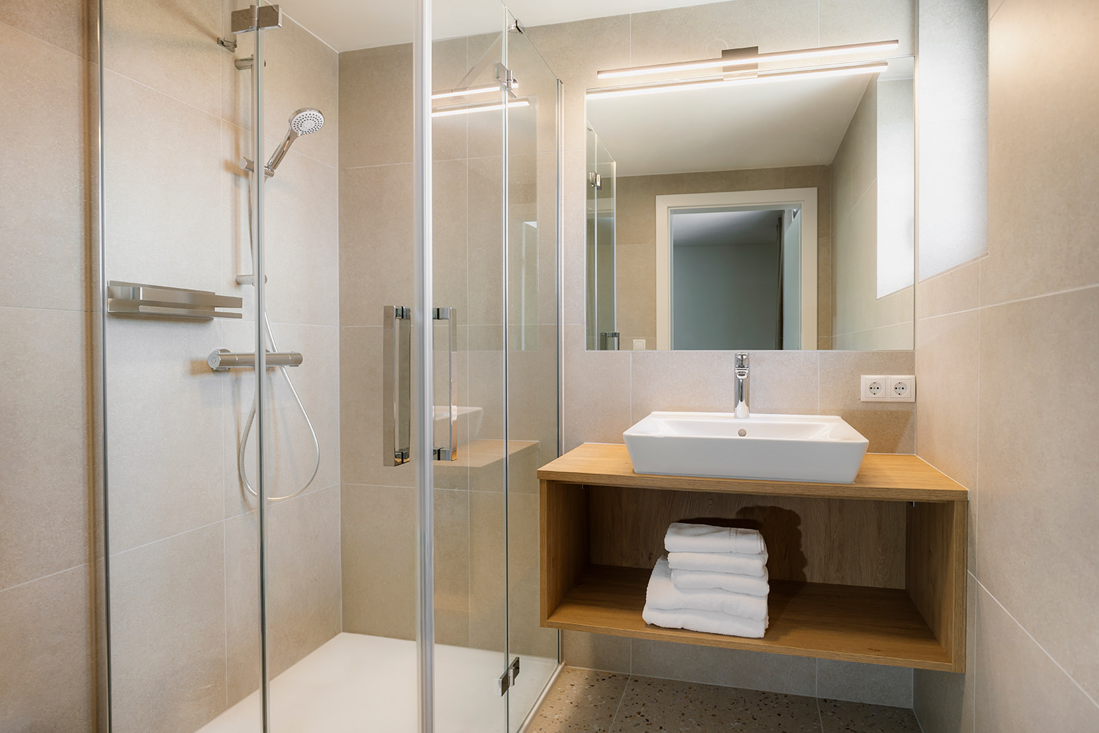 Modernes Badezimmer mit Dusche, Waschtisch und Handtüchern im Zollquartier